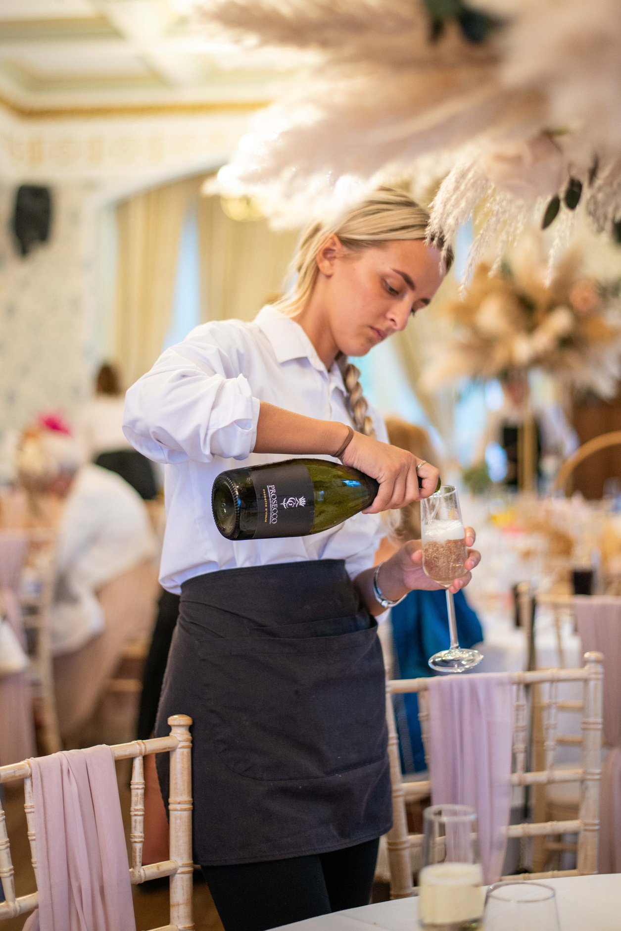 a person pours wine into a glass at a wedding reception